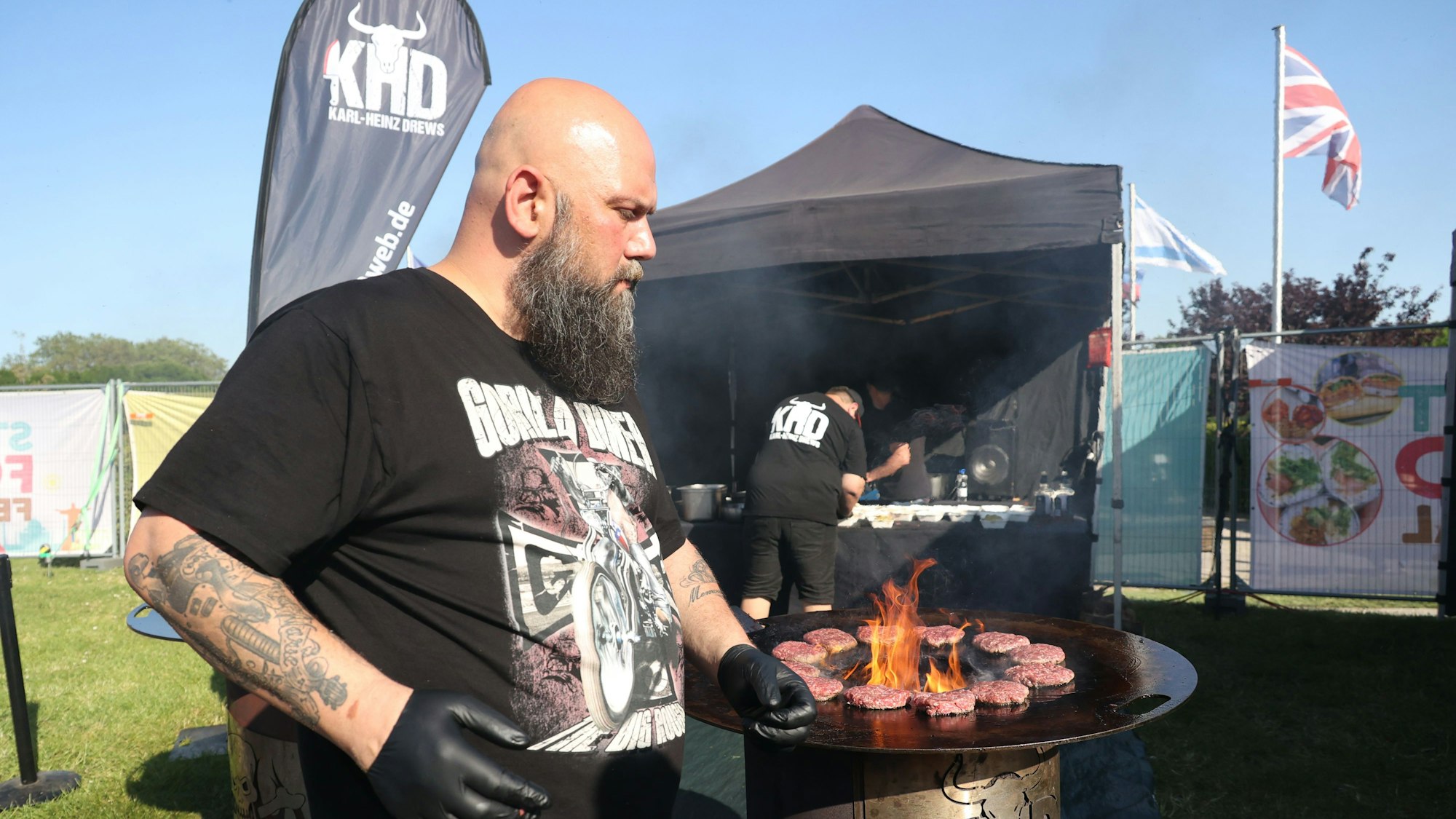 Mann grillt Burger am offenen Feuer