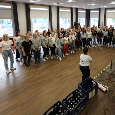 Der Chor steht im Halbkreis um den Chorleiter herum.