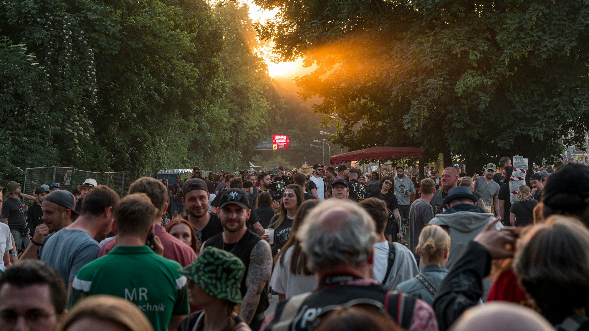 Festivalbesucher und -besucherinnen gehen bei abendlichem Licht über das Rock im Park Gelände.