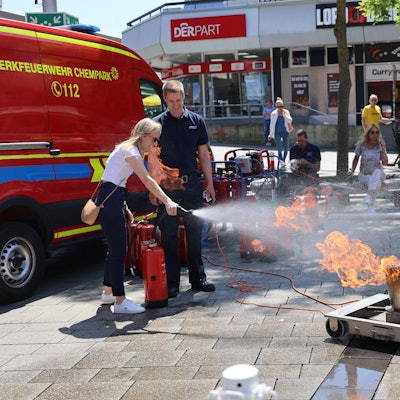 Eine Frau löscht mit einem Feuerlöscher einen künstlichen Brand