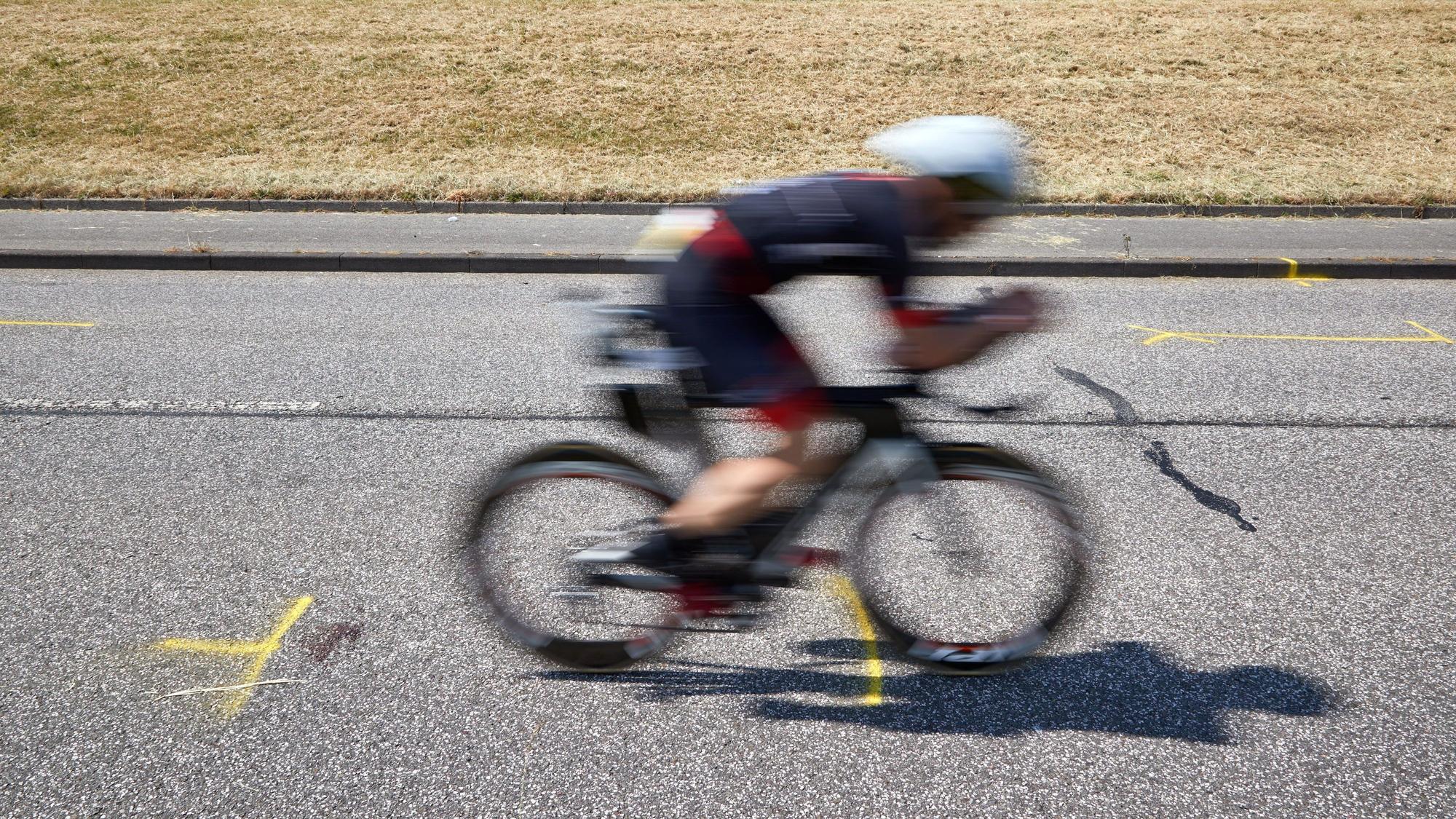 Tragödie bei Ironman-EM in Hamburg: Ein Triathlet fährt auf dem Rad an der Unglückstelle auf dem Gaueter Hauptdeich vorbei.