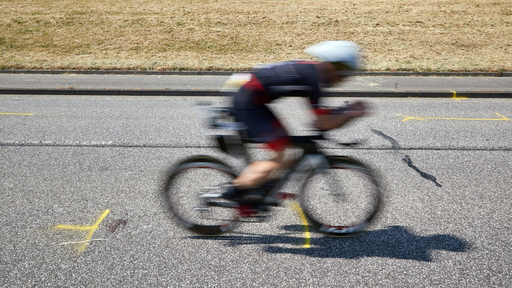 Tragödie bei Ironman-EM in Hamburg: Ein Triathlet fährt auf dem Rad an der Unglückstelle auf dem Gaueter Hauptdeich vorbei.