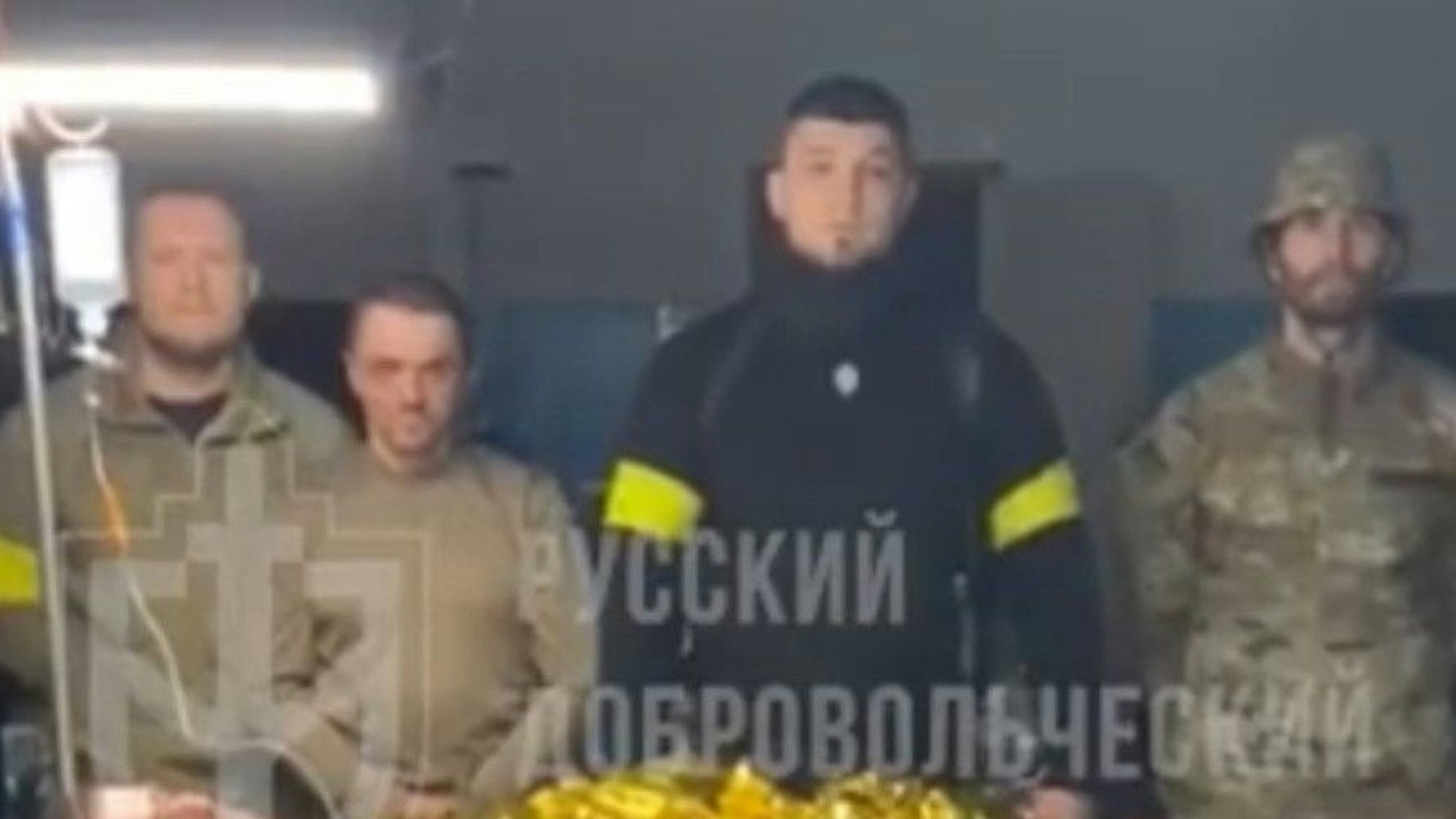 Kämpfer des „Russischen Freiwilligenkorps“ posieren in einem Video mit einem mutmaßlichen russischen Kriegsgefangenen. Der Anführer der Gruppe, schwarz gekleidet, ist der Neonazi Denis Kapustin, der mehrere Jahre in Köln gelebt hat.