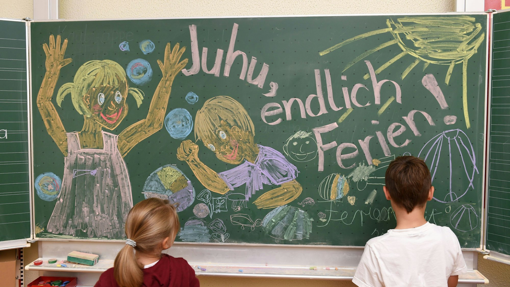 ARCHIV - 29.07.2015, Baden-Württemberg, Weißenau: Erst- und Zweitklässler malen in der Grundschule in Weißenau (Baden-Württemberg) bei Ravensburg am letzten Schultag des Jahres für den Fotografen ein Bild an die Tafel, auf dem «Juhu, endlich Ferien», zu lesen ist.
Alle Schülerinnen und Schüler in einem Bundesland starten am selben Tag in die Ferien. (zu dpa: «Keine Atteste mehr für Schulschwänzer») Foto: Felix Kästle/dpa - Honorarfrei nur für Bezieher des Dienstes dpa-Nachrichten für Kinder +++ dpa-Nachrichten für Kinder +++