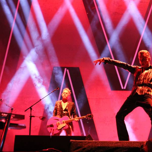 Dave Gahan (rechts) und Martin Gore in der Merkur-Spiel-Arena in Düsseldorf am 4. Juni 2023. Gahan hält seine Arme weit ausgestreckt, Gore spielt eine pinke Gitarre.