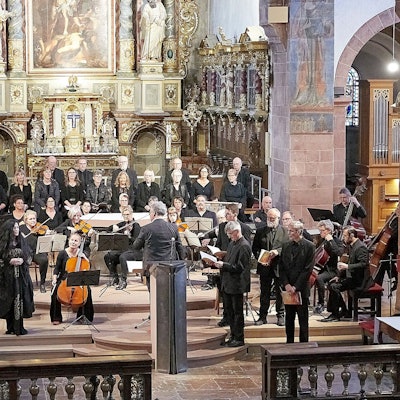 Ein Chor und ein Orchester musizieren im Altarraum der Steinfelder Basilika.