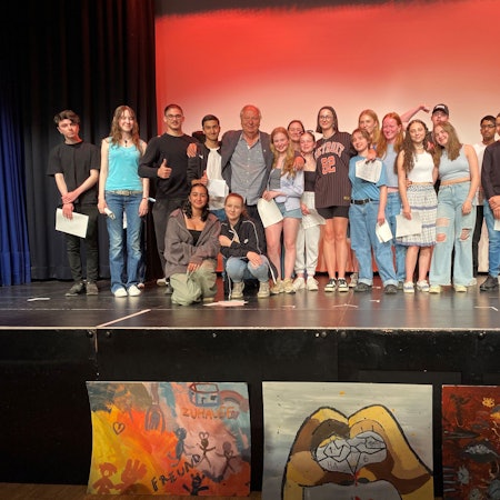 Einige der Schülerinnen und Schüler aus Chorweiler, Ehrenfeld, Höhenberg und Innenstadt stehen mit Wilfried Schmickler und Stephan Brings auf der Bühne und präsentieren ihre Erfahrungen beim innerstädtischen Schüleraustausch.