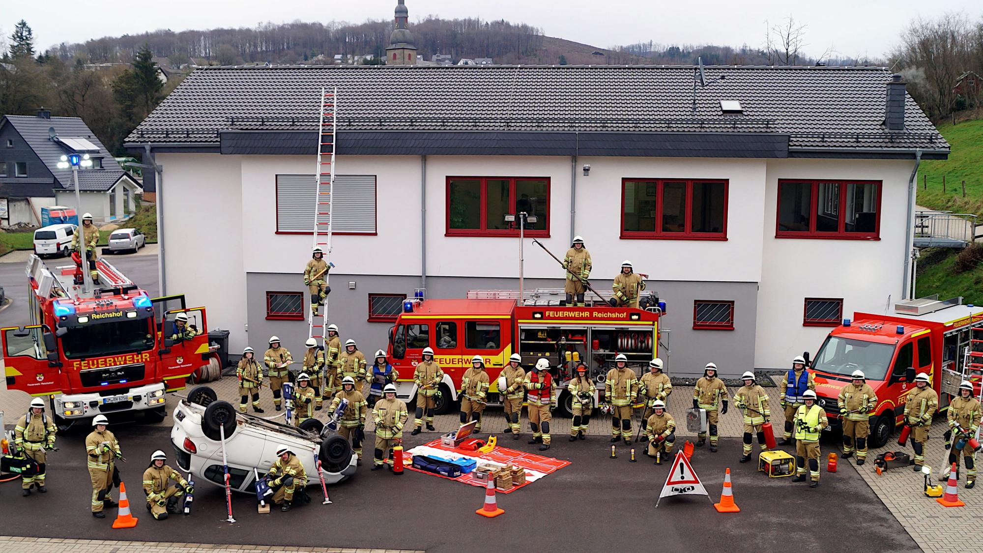 Die Kameradinnen und Kameraden des Löschzugs stehen vor ihrer Wache und ihren Fahrzeugen.