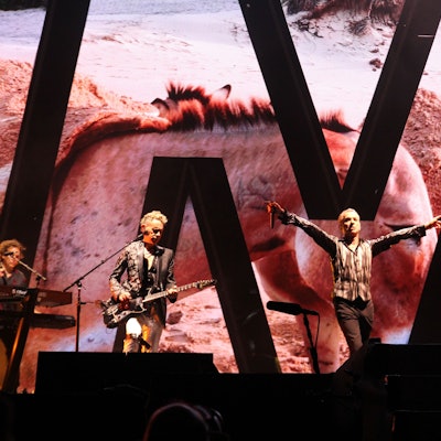 Depeche Mode (Dave Gahan und Martin Gore) auf der Bühne in der Merkur-Spiel-Arena in Düsseldorf. Gahan hat die Arme Richtung Publikum ausgebreitet.