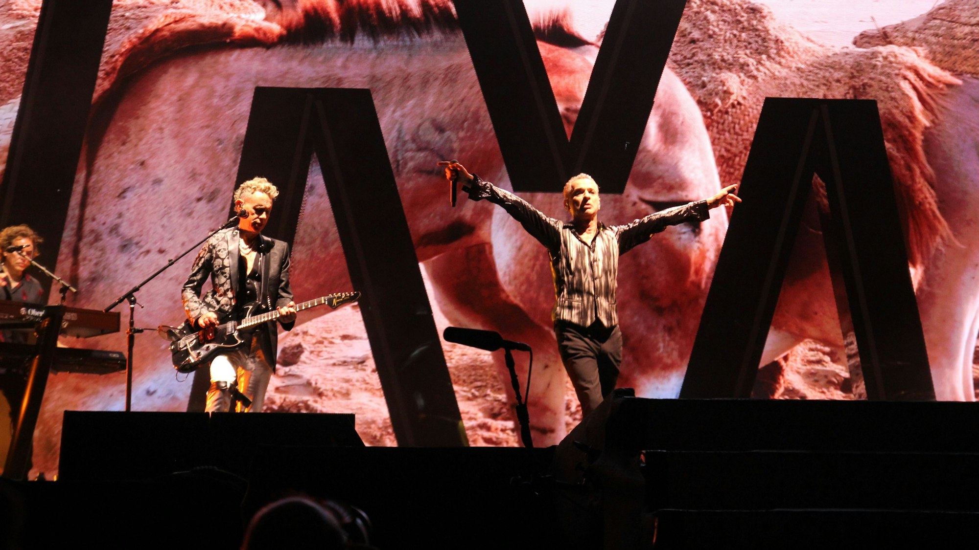 Depeche Mode (Dave Gahan und Martin Gore) auf der Bühne in der Merkur-Spiel-Arena in Düsseldorf. Gahan hat die Arme Richtung Publikum ausgebreitet.