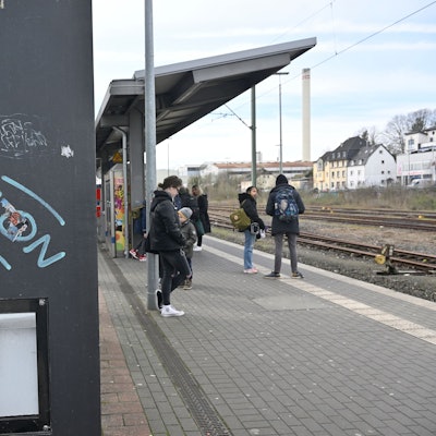 Menschen stehen am Bahnhof.