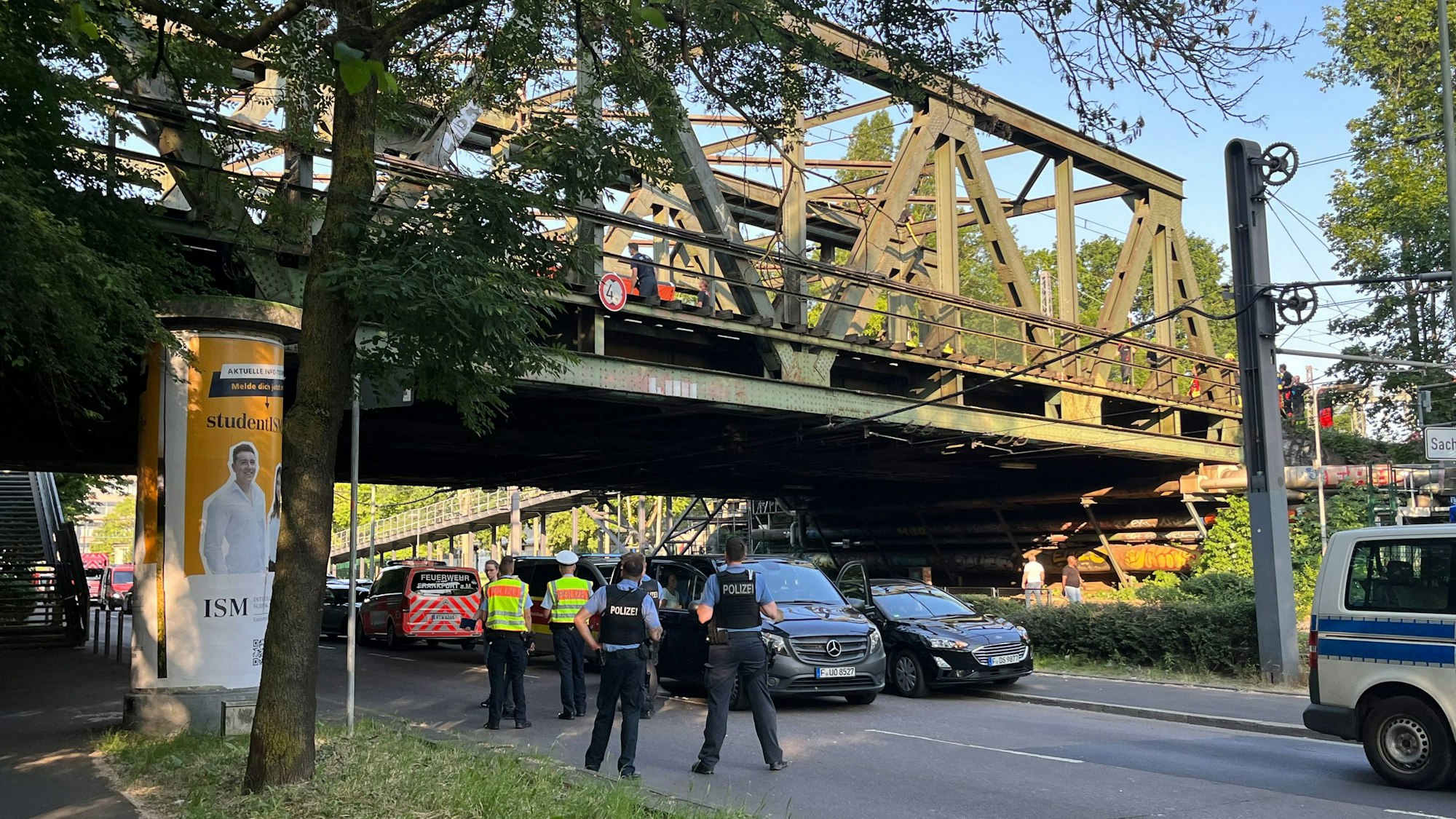 Einsatzkräfte stehen auf und unter einer Eisenbahnbrücke. Der Polizeieinsatz unweit des Frankfurter Hauptbahnhofs führte Montagnachmittag zu zahlreichen Zugausfällen sowohl im Nah- als auch im Fernverkehr.