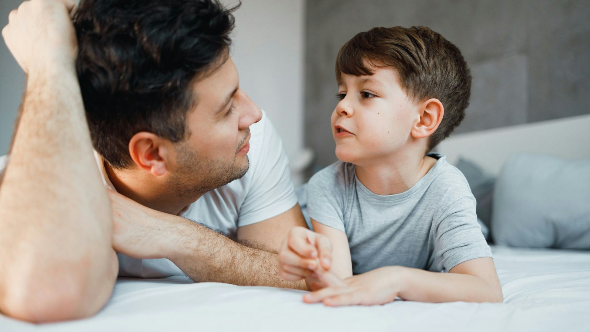 Father and his 7 years old son are talking in the bed. Foto: Getty Images/Georgijevic