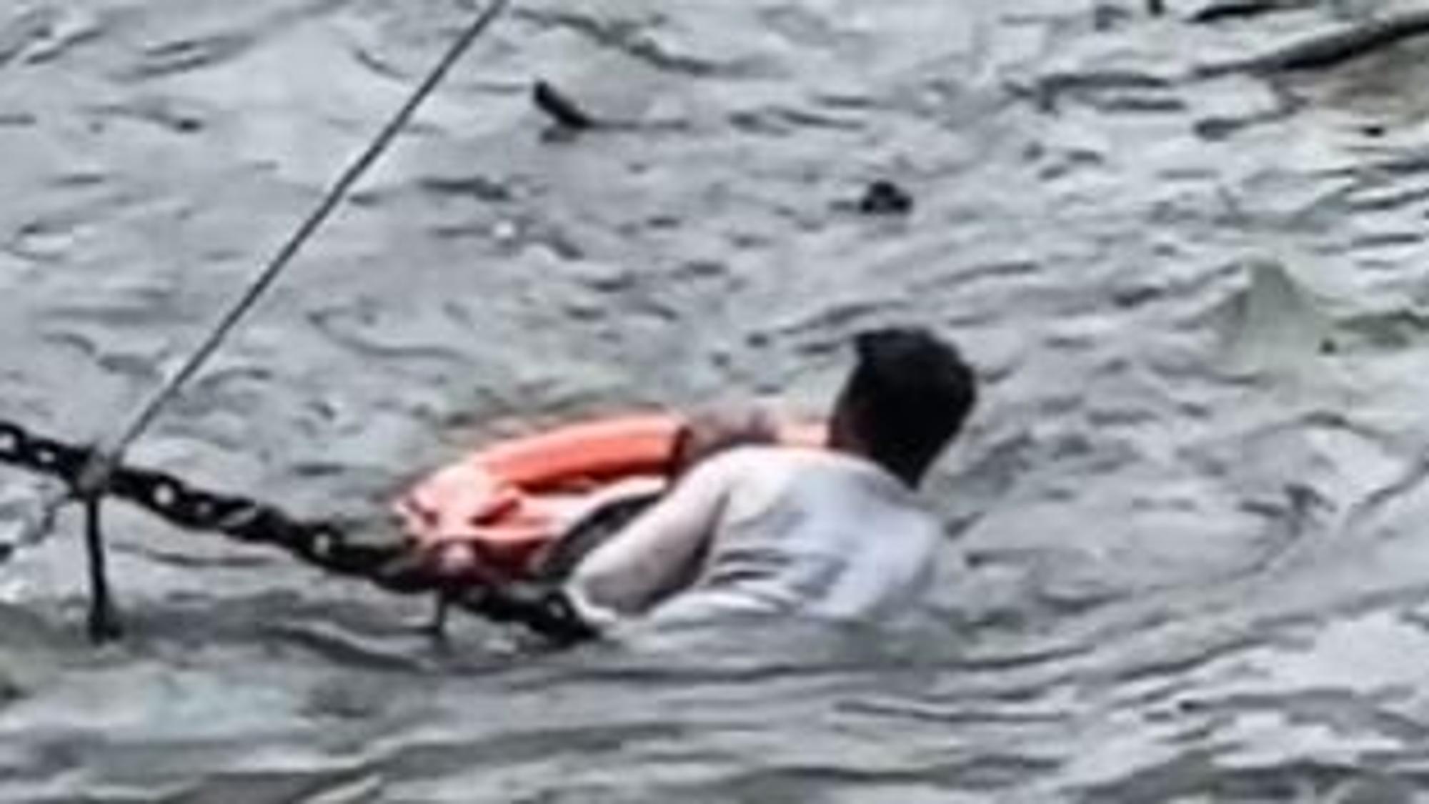 Ein Mann hält einen anderen Mann im Rhein über Wasser.