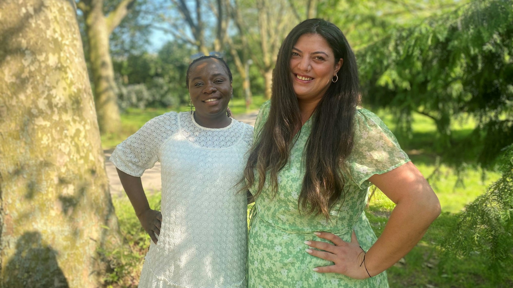 Die Mutter und deren Betreuerin stehen Arm in Arm in einem Park.