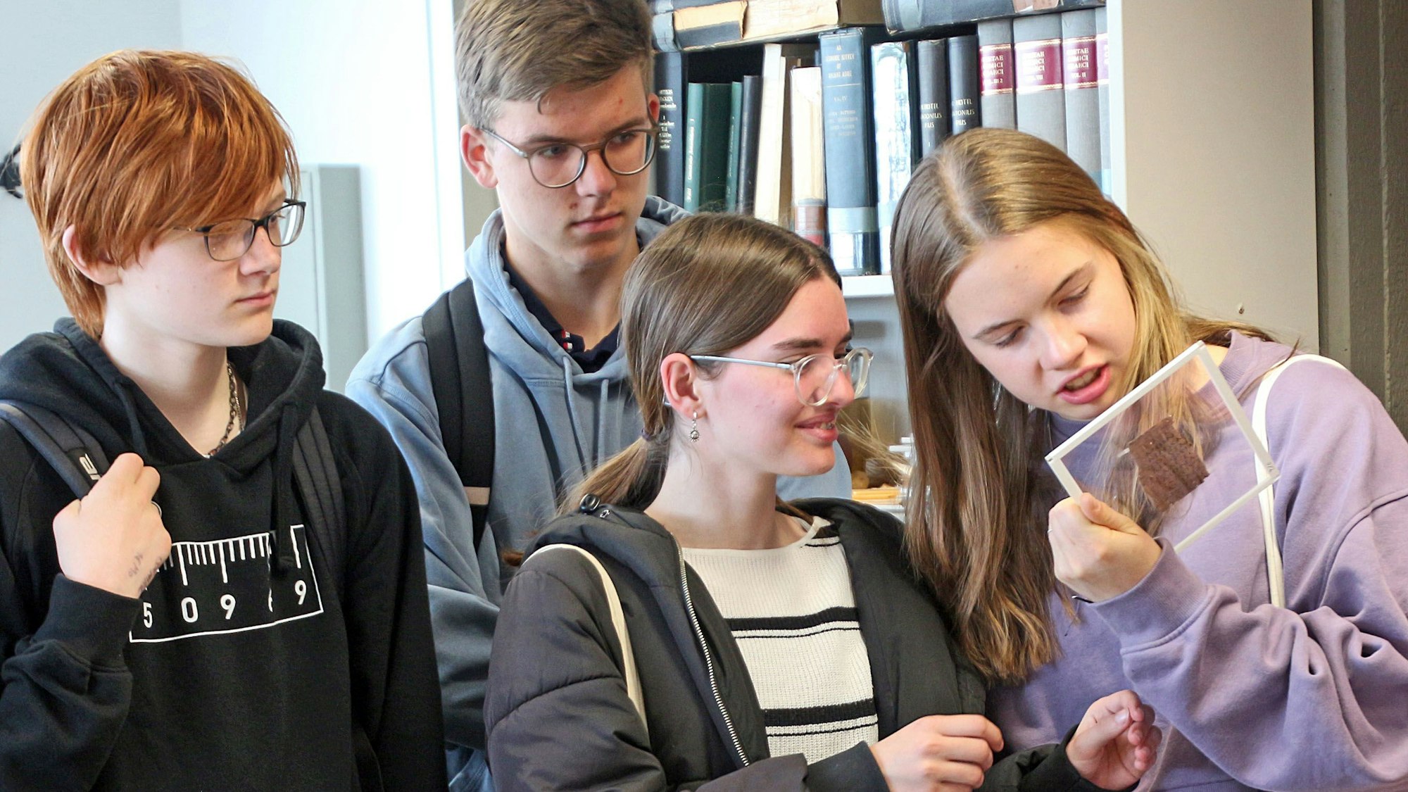 Schülerinnen und Schüler betrachten ein Papyrusfragment aus der Sammlung der Uni Köln.