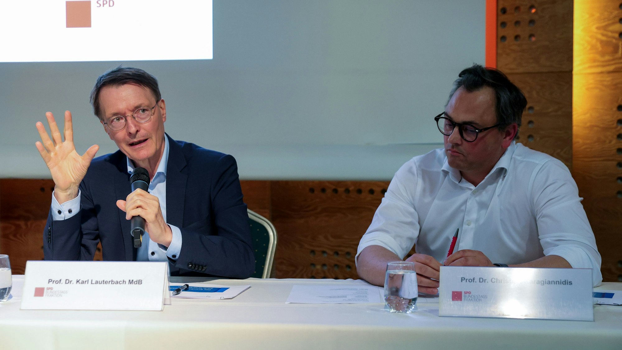 Prof. Dr. Karl Lauterbach und Prof. Dr. Christian Karagiannidis sitzen an einem Tisch – Lauterbach spricht ins Mikrofon.