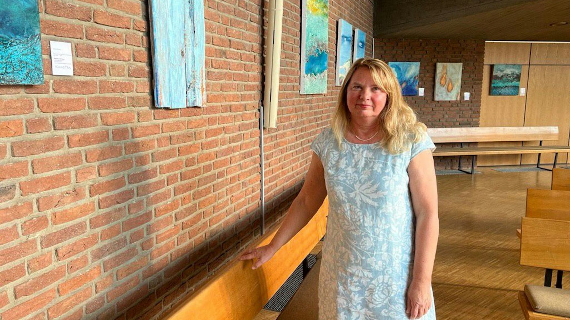 Martin Tenhagen vor einigen Werken ihrer Ausstellung „Farbenklang“ in der evangelischen Kirche Quettingen.