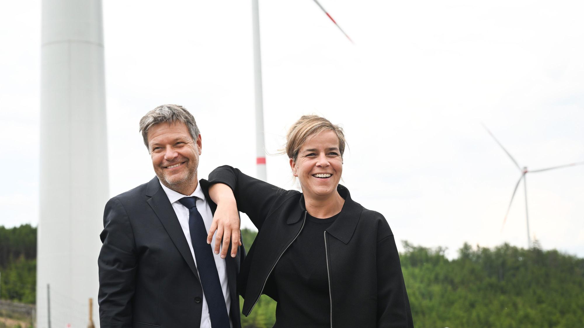 06.06.2023, Nordrhein-Westfalen, Bad Berleburg: Robert Habeck (l), Bundeswirtschaftsminister, und NRW-Wirtschaftsministerin Mona Neubaur (beide Grüne), scherzen vor Windrädern zur Stromerzeugung. Die Wittgenstein Gruppe sowie der Landesverband Erneuerbare Energien NRW nehmen den seit Herbst 2022 bestehenden Wald-Windpark Arfeld mit vier Windrädern offiziell in Betrieb. Foto: Federico Gambarini/dpa +++ dpa-Bildfunk +++