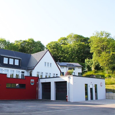 Das Bild zeigt vorne den Neubau des Feuerwehrgerätehauses in Kronenburg, dahinter und etwas erhöht im Hang das Dorfgemeinschaftshaus.