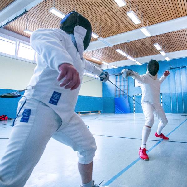 Zwei Sportler im Ganzkörper-Schutzanzug fechten.