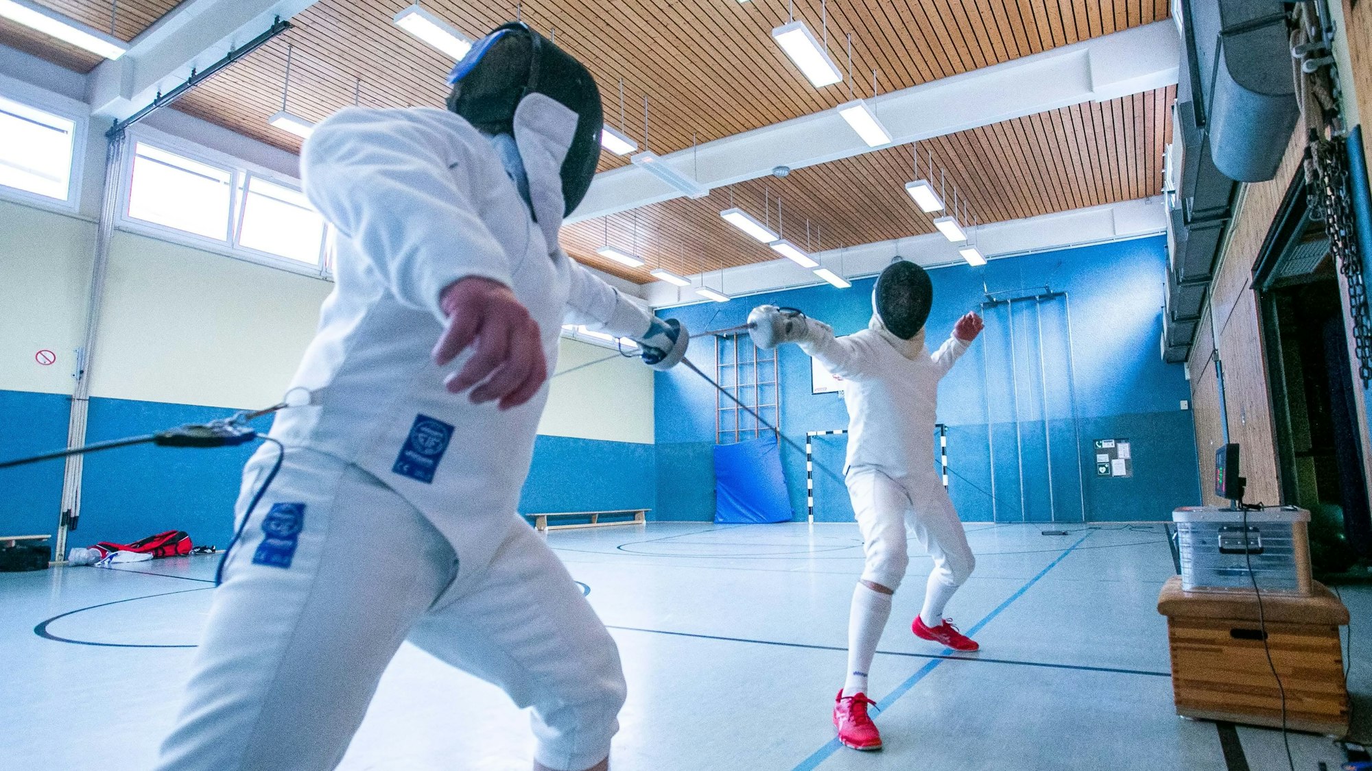 Zwei Sportler im Ganzkörper-Schutzanzug fechten.