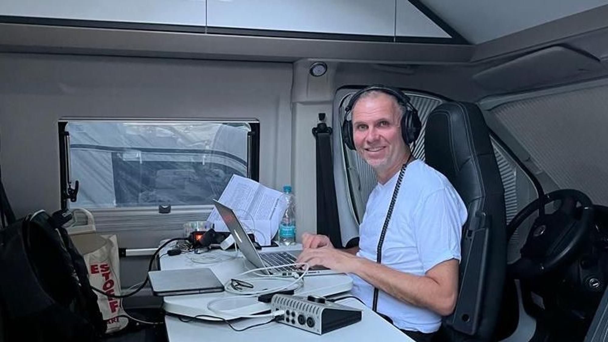 Wolfgang Löhr sitzt im Wohnwagen an einem Laptop.