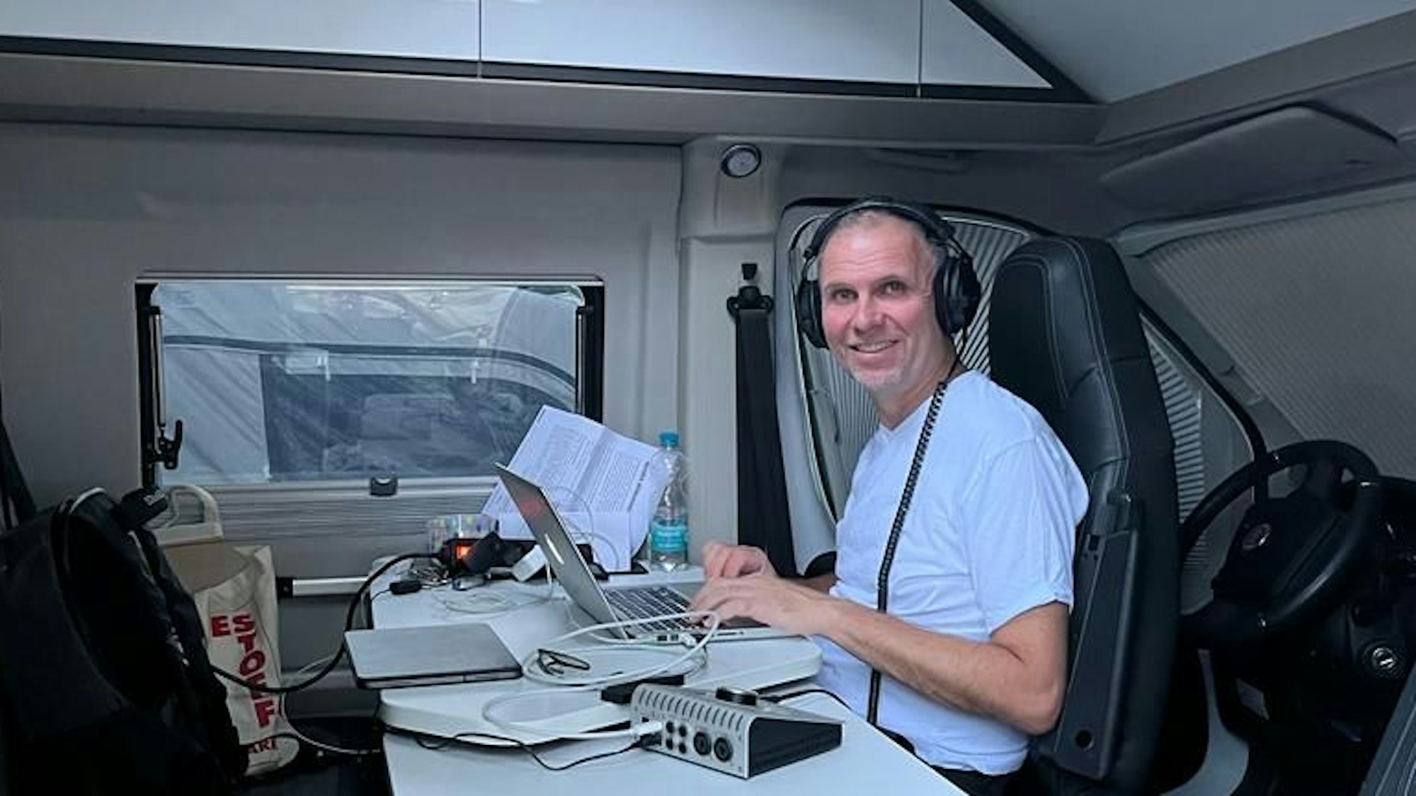 Wolfgang Löhr sitzt im Wohnwagen an einem Laptop.