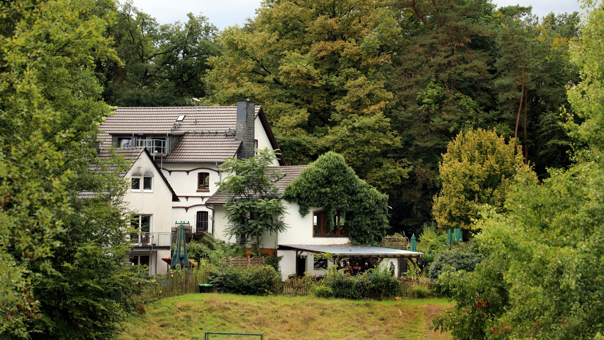 Zwischen Bäumen steht ein Haus.