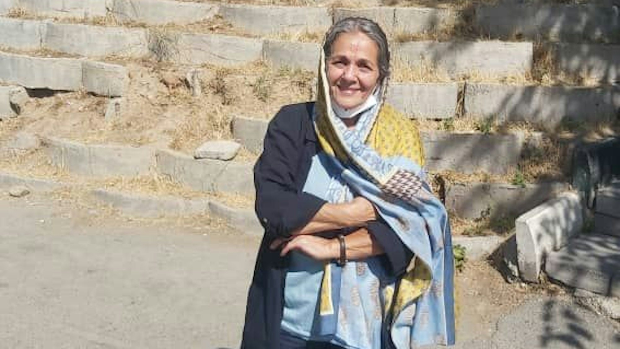 Nahid Taghavi trägt ein hellblaues Kopftuch mit gelben Mustern. Im Hintergrund eine Treppe aus groben Steinen, die zum Gefängnis führt.