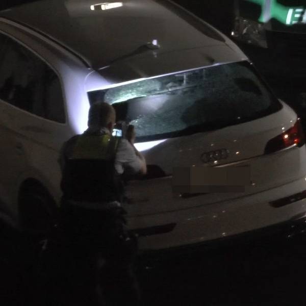Ein weißes Fahrzeug wird von Polizisten untersucht.