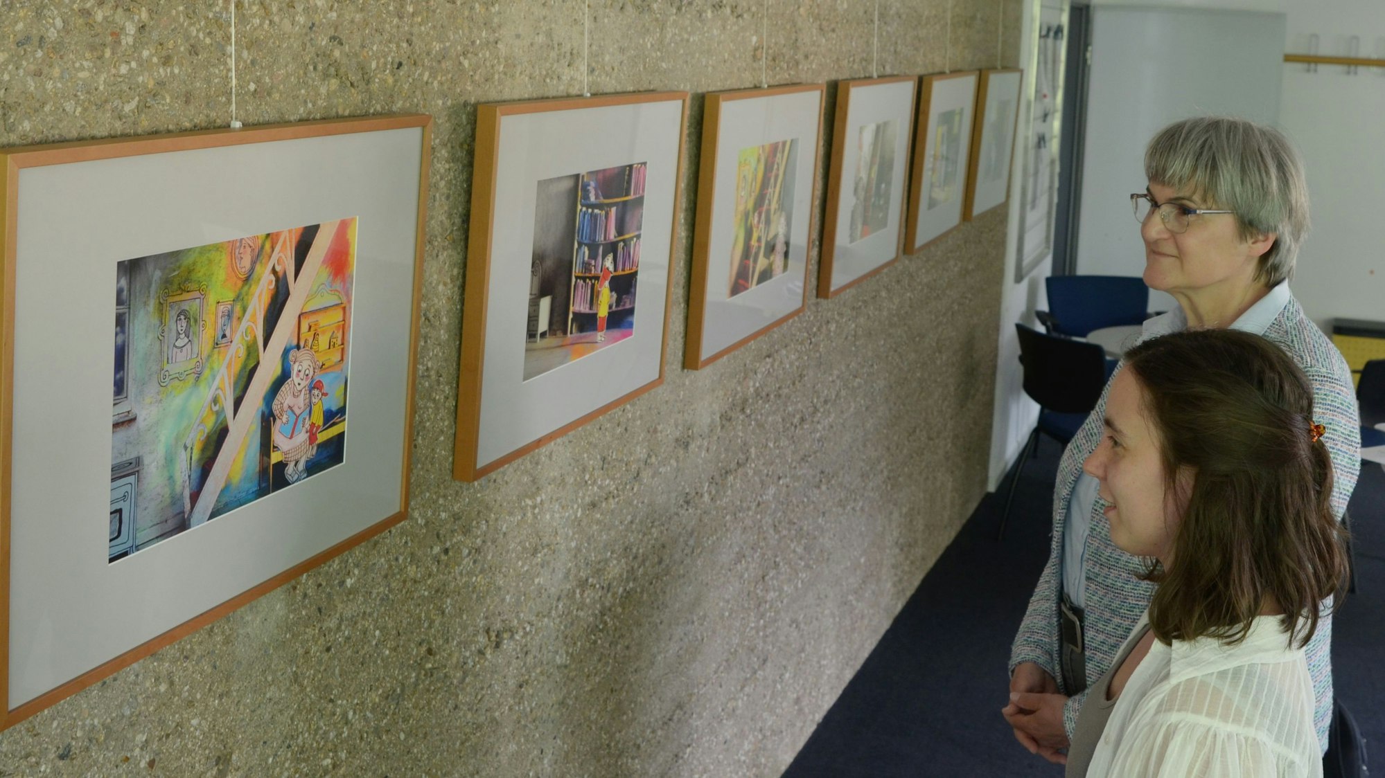 Das Foto zeigt zwei Frauen, die im Haus der Familie in Euskirchen Bilder einer Ausstellung betrachten.