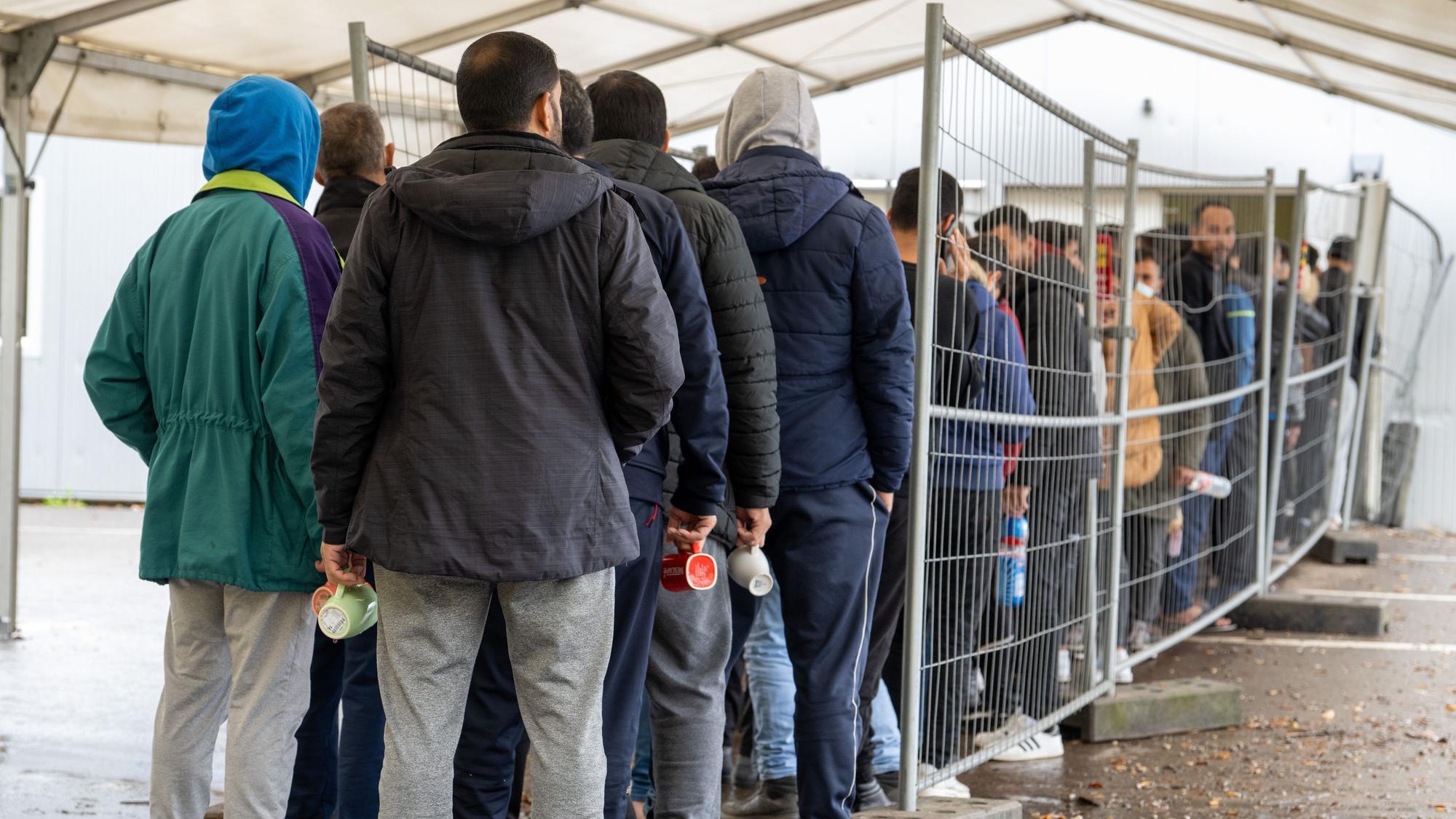 In der Landeserstaufnahmestelle (LEA) warten Geflüchtete in einer Schlange.
