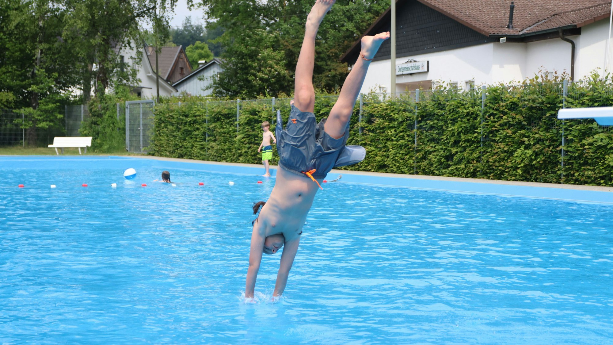 Ein Junge macht in einem Freibad einen Köpper ins Wasser.