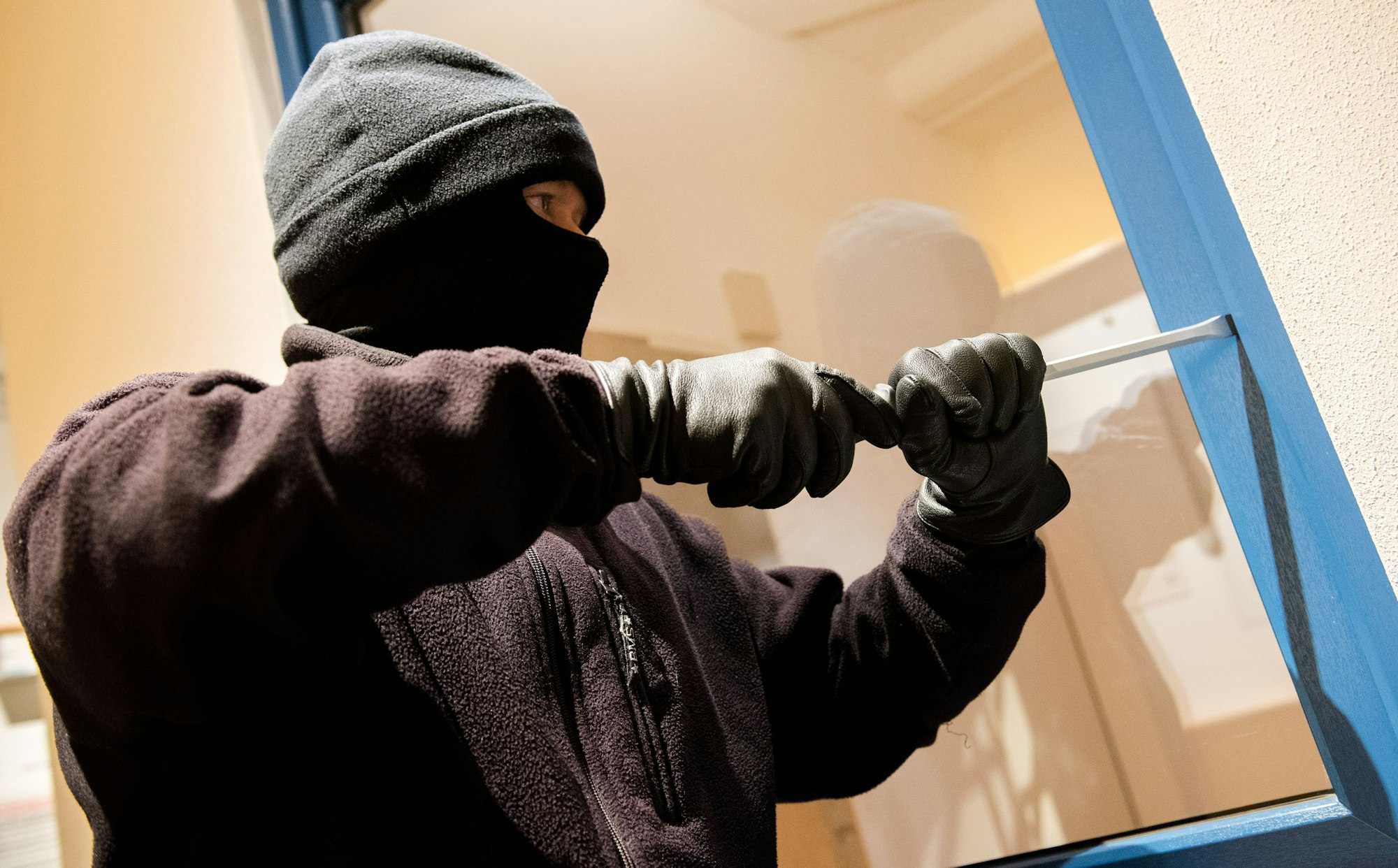 Ein als Einbrecher verkleideter Mann hebelt in der Kriminalpolizeilichen Beratungsstelle der Polizei ein Fenster auf. Dank guter Prävention sind nach Angaben der Polizei 51,3 Prozent der Einbruchsversuche in der Hansestadt in 2021 gescheitert. (zu dpa «Mehrzahl der Einbruchsversuche in Hamburg scheitert - Gute Prävention») +++ dpa-Bildfunk +++