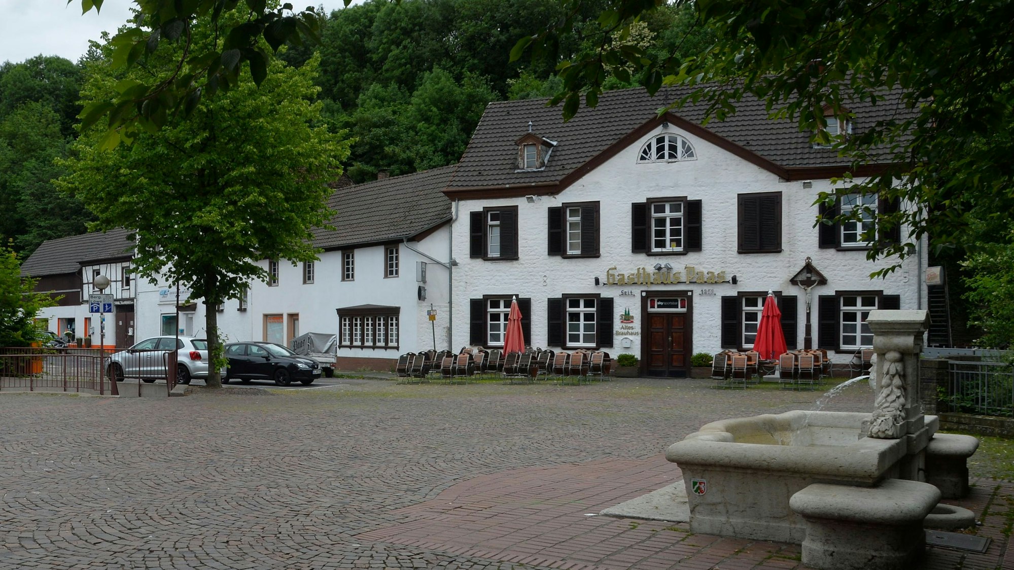 Hinter einem Platz liegt ein Gebäude mit der Aufschrift Gasthaus Paas.