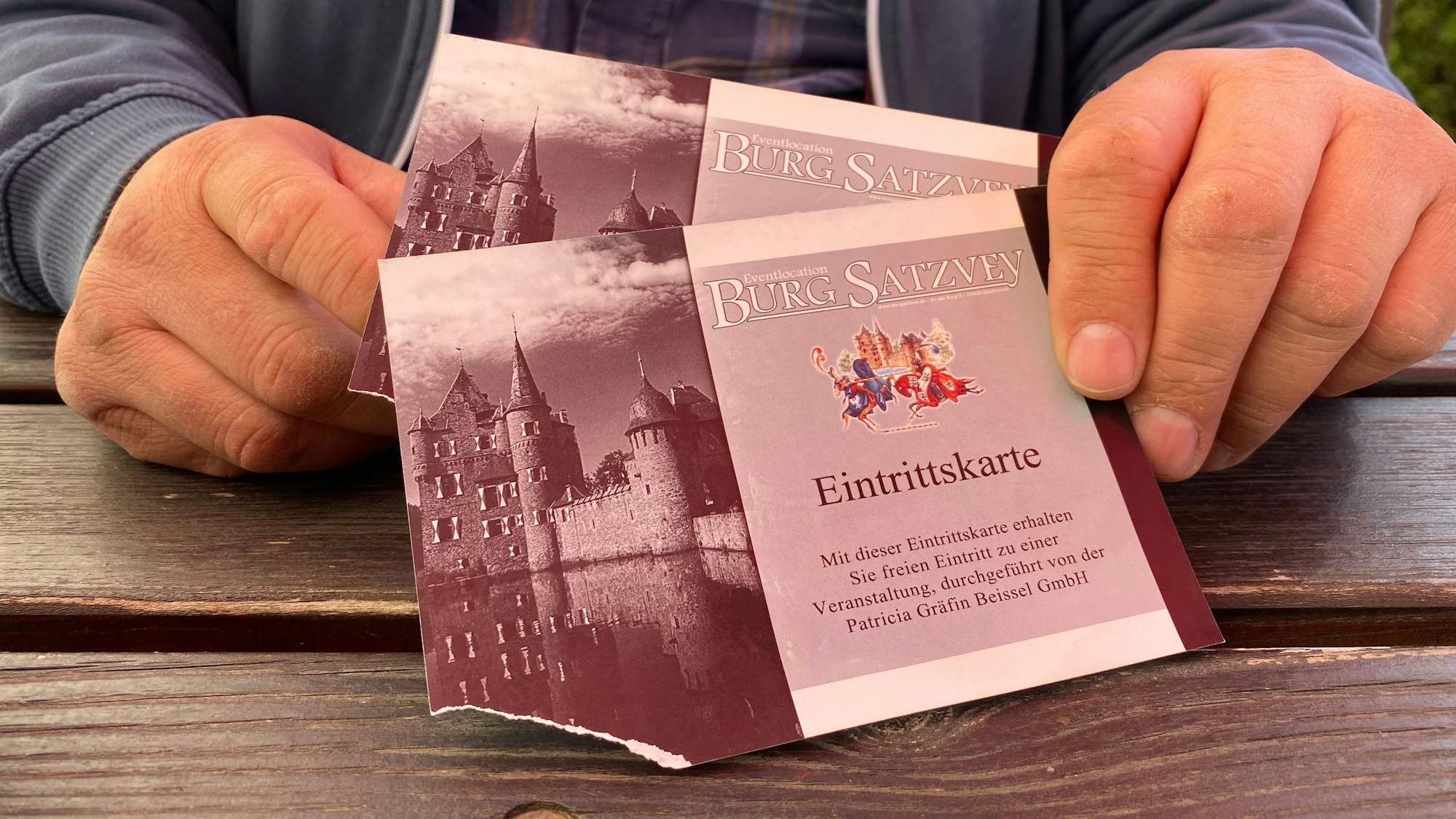 Zu sehen sind zwei Eintrittskarten für die Burg Satzvey uind zwei Hände, die sie festhalten.
