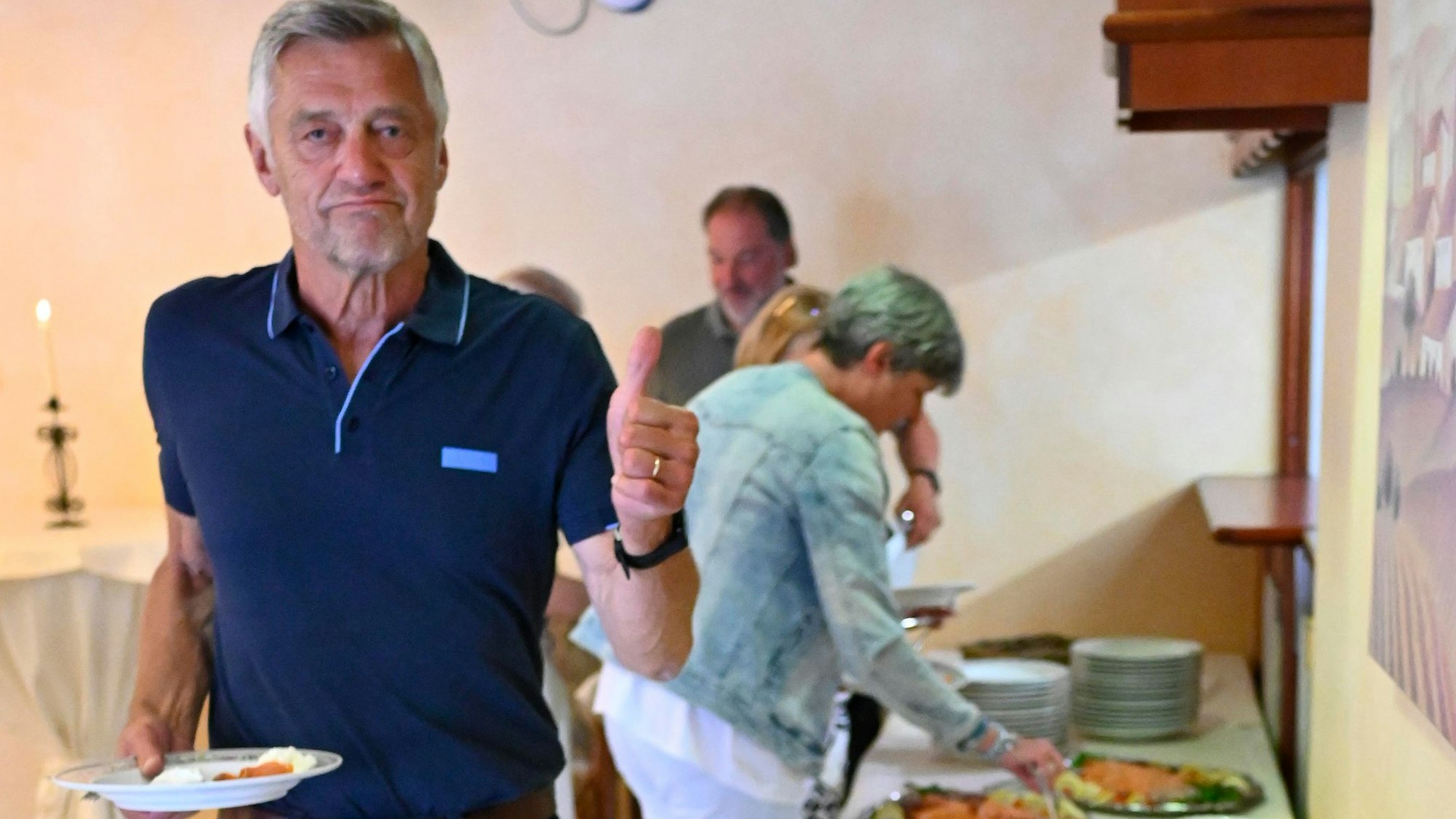 Ein Mann mit einem Teller auf der Hand hat sich an einem Büfett etwas zu essen geholt.
