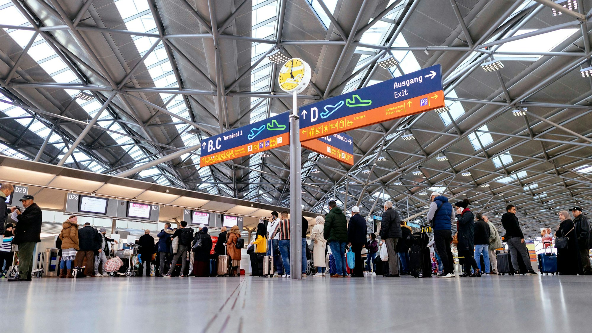 Zu sehen ist eine Halle im Flughafen Köln/Bonn in der Menschen warten.