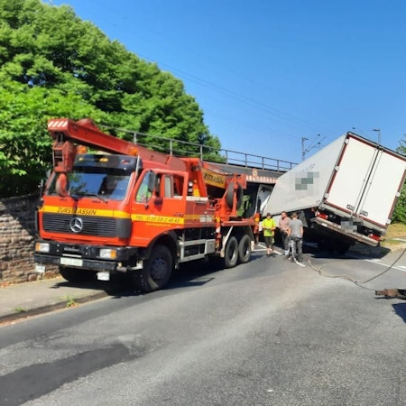 Ein Lkw steckt unter einer Eisenbahnbrücke.