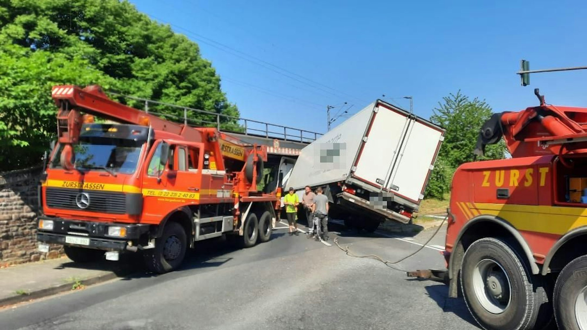 Ein Lkw steckt unter einer Eisenbahnbrücke.