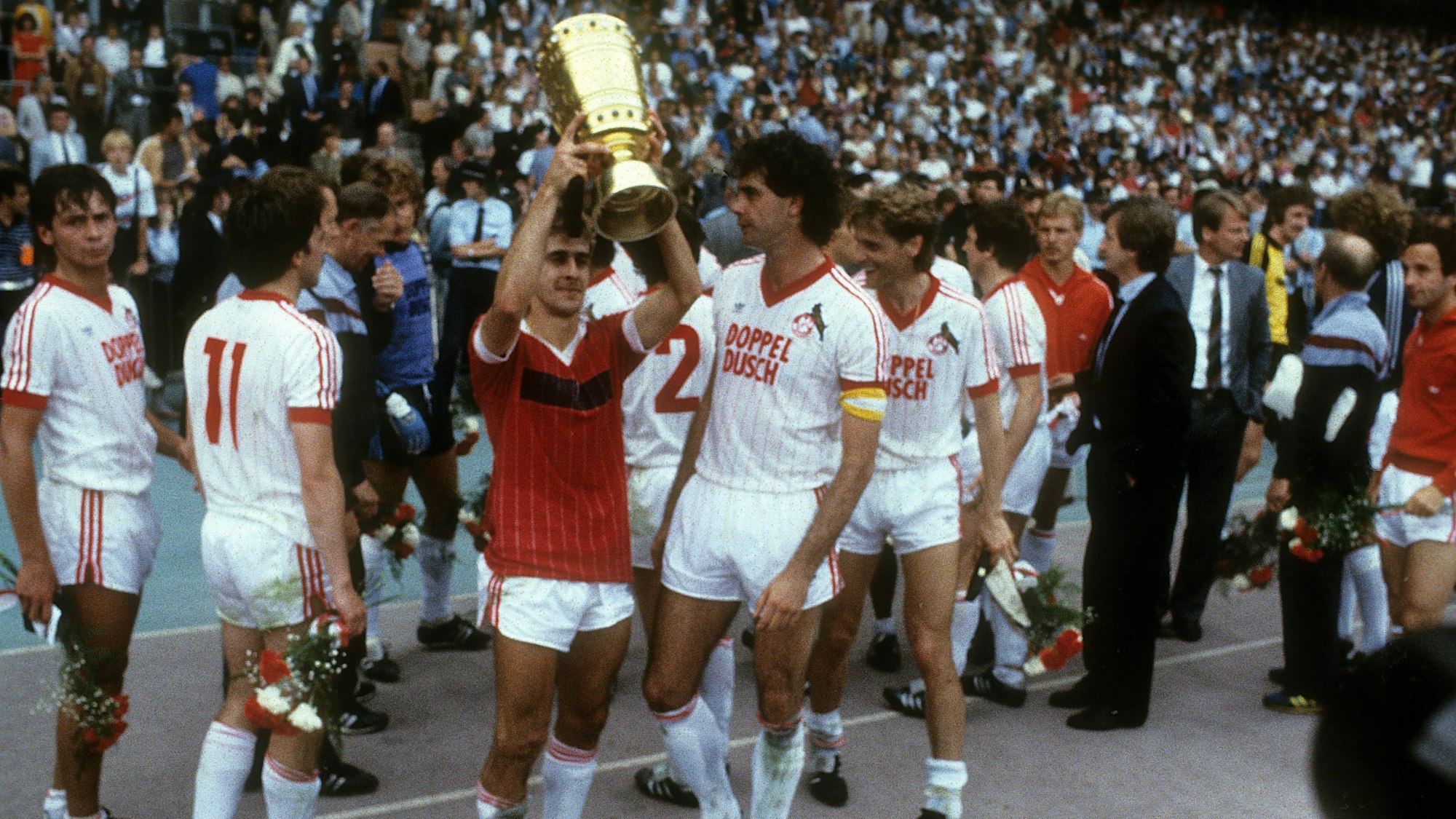 Spieler des 1. FC Köln freuen sich über den Pokalsieg. Einer stemmt die Trophäe in die Höhe.