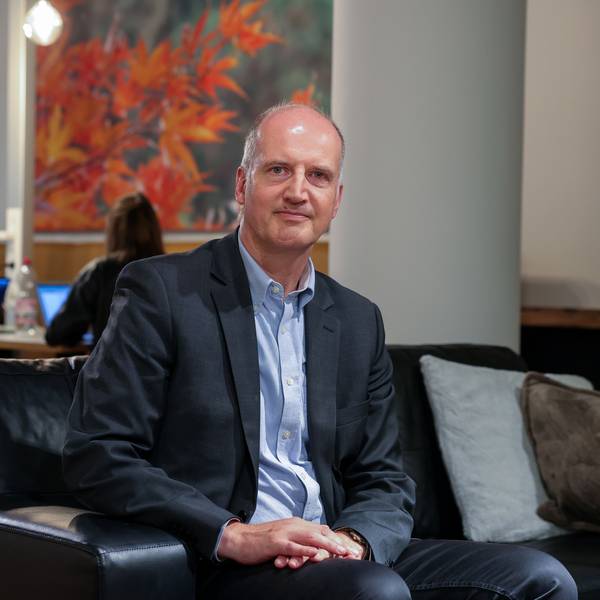 Prof. Dr. Tobias Engelsleben sitzt auf einem Sofa und schaut in die Kamera.