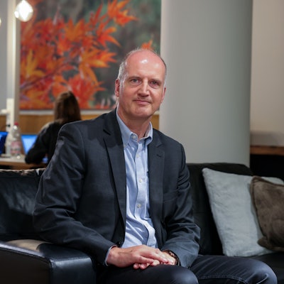 Prof. Dr. Tobias Engelsleben sitzt auf einem Sofa und schaut in die Kamera.