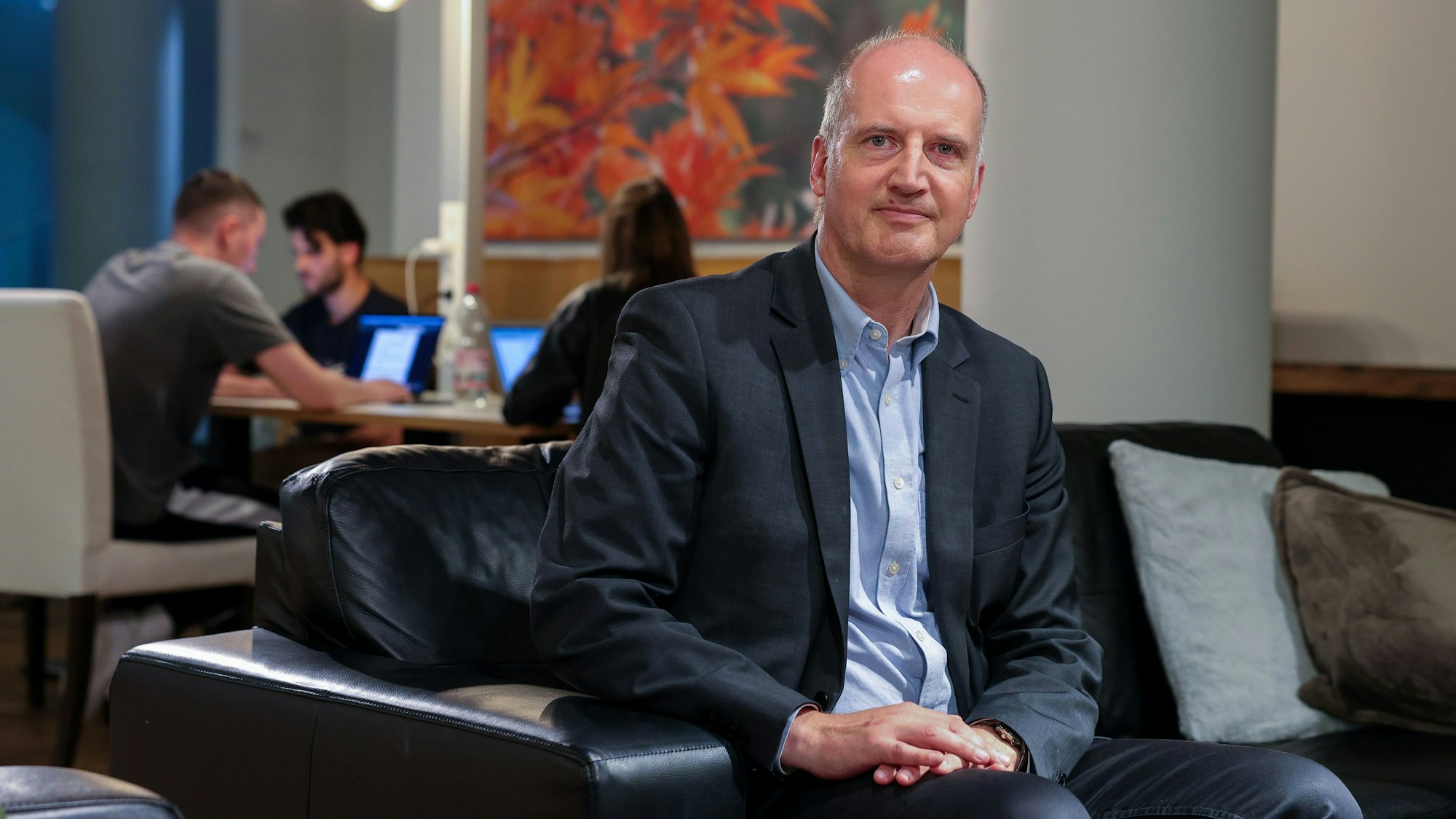 Prof. Dr. Tobias Engelsleben sitzt auf einem Sofa und schaut in die Kamera.