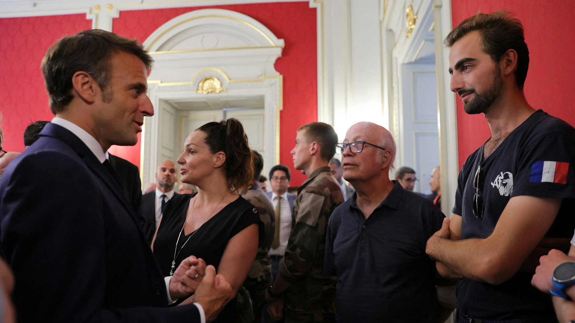 Die beiden Männer stehen sich gegenüber. Macron im Anzug und Henri im T-Shirt.