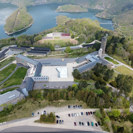 Das Luftbild zeigt den Bereich rund um den Adlerhof in Vogelsang, im Hintergrund den Urftsee.