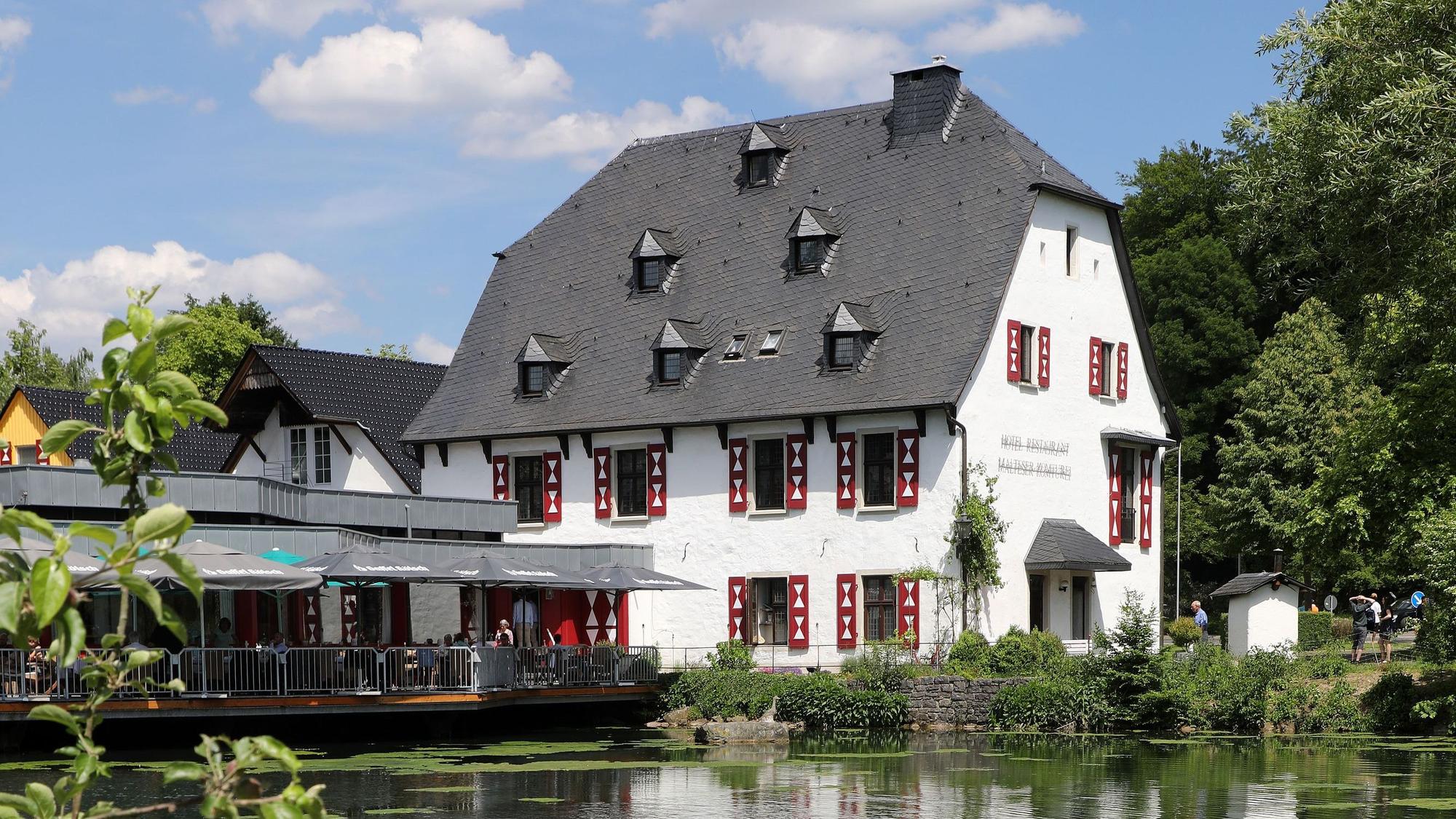 Ein Fachwerkhaus liegt hinter einem See.