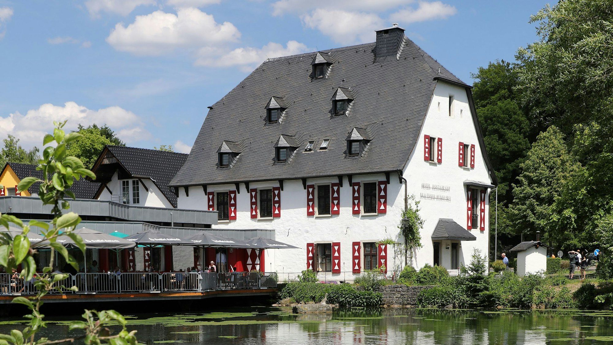 Ein Fachwerkhaus liegt hinter einem See.