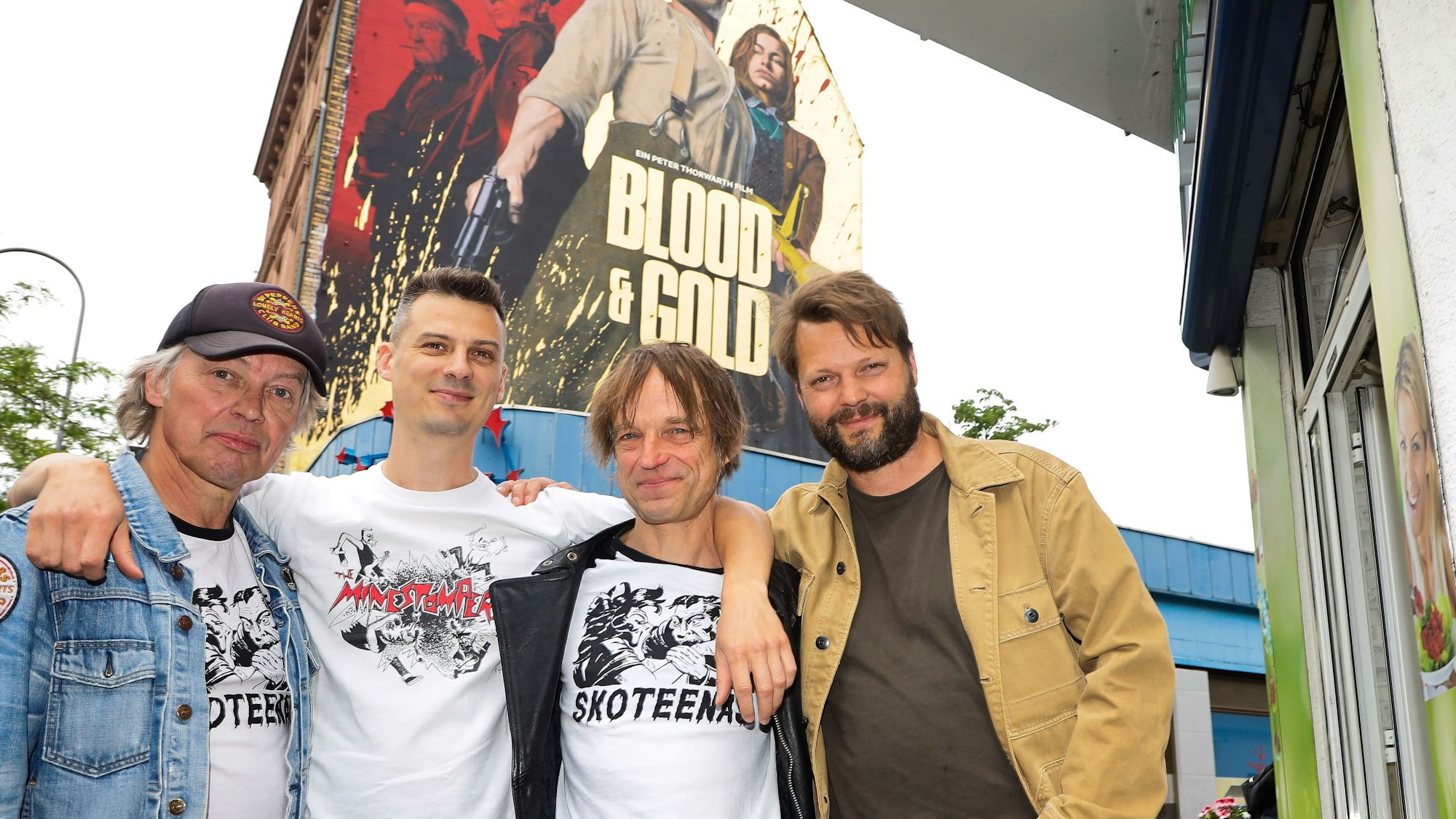 Wolly Düse, Max Jakuschew und Ingo Ruttke von der Kölner Band Skoteenas stehen mit Regisseur Peter Thorwarth auf der Venloer Straße, Ecke Körnerstraße